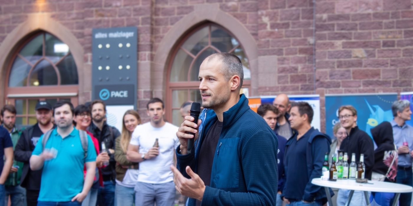 Lukas Schoen spricht mit Mikrofon vor Publikum bei einer Abendveranstaltung